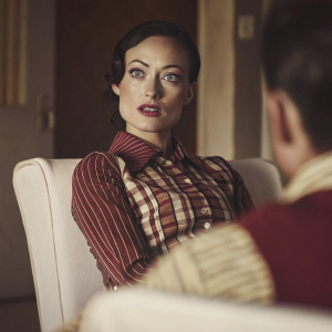 Olivia Wilde as Dr. Remy Hadley from 'House'. Intense look. Stylish dark hair. Sitting on white chair in blurred background. Indoor setting