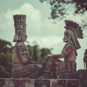 Ancient Mayan sculpture depicting ceremonial figures. One figure with tall hat, another with feathered headdress. Located in Chichen Itza, Yucatan, Mexico. Photo