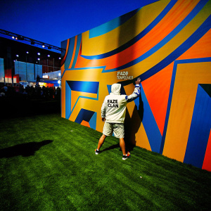 FaZe Temperr, with Faze Clan branding, standing in front of an abstract colorful wall. Gaming conference