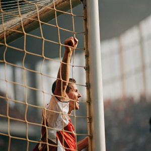 Edin Dzeko, sporting an Arsenal jersey, scoring a goal amidst a blurry stadium crowd.