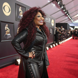 Chaka Khan at the Grammy Awards, vibrant and joyful, adorned in a black leather outfit with a red carpet backdrop