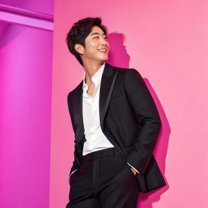 Kim Hyun-Joong in a sleek black suit with a white shirt, posing for a magazine cover. Neon pink background.