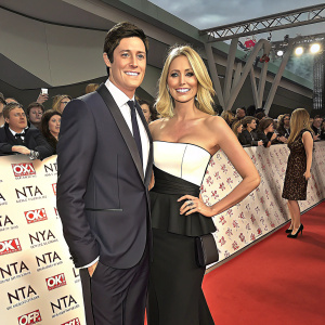 Vernon Kay and Tess Daly at the National Television Awards. Vernon in a dark suit, Tess in a white and black strapless top with a structured black skirt. Formal event setting with repeated logos and a crowd.