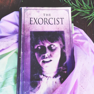 Book cover for 'The Exorcist'. Dark and eerie atmosphere, featuring a face with twisted expression.