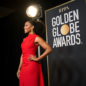 Naomi Ackie at the Golden Globe Awards, in a stylish red dress. Black background with spotlight effect