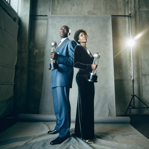 Morris Chestnut and Pam Byse, both in formal attire, at the NAACP Image Awards. Blue suit and black dress respectively. Posing with award statues. Studio backdrop.