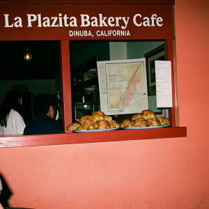 La Plazita Bakery Cafe, a charming eatery in Dinuba, California. Features golden brown pastries, warm color palette, and detailed map location guide. Open sign with hours of operation prominently displayed.