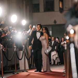 Jake T. Austin and Cierra Ramirez at a glamorous movie premiere. Wearing formal attire, black tuxedo and pink sequined gown respectively. Crowds cheering and flashing cameras