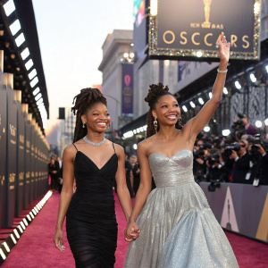 Chloe and Halle Bailey, dressed in elegant gowns, walking down the carpet at the Oscars premiere.
