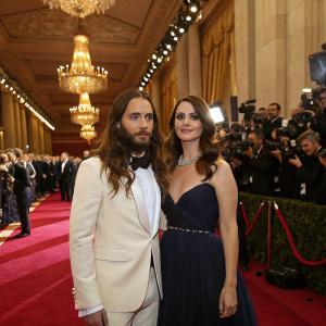 Jared Leto and Lana Del Rey attend a star-studded gala. Ornate decor, red carpet, and paparazzi in attendance.
