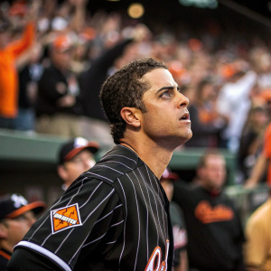 Brian Roberts, Baltimore Orioles player, intense focus during game. Wearing black jersey with white stripes. Crowd cheering in background