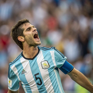Fernando Gago, in vibrant Argentina jersey with number 5, displaying intense emotion. Crowd in background, blurred.