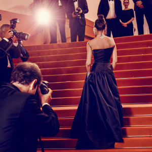 Victoria Beckham, in a stunning black satin dress, at the Cannes Film Festival. Red carpet scene with flashing cameras and paparazzi.