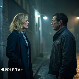 Elisabeth Shue and Jason Isaacs in a tense scene from 'The Mosquito Coast'. Gloomy alley with dim lighting. Logo of Apple TV+ at the bottom.