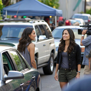 Meaghan Rath and Katrina Law on the set of Hawaii Five-0, amidst parked cars and bustling crew.