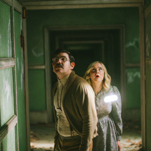 A cinematic scene from Wolfenstein. Characters in a dimly lit, ominous hallway. A man with a mustache and a blonde girl with terrified expressions.