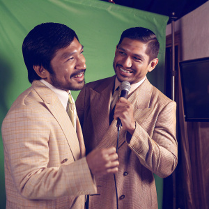 Manny Pacquiao and Amir Khan at a press conference. Both wear suits and sport smiles. Against green screen backdrop.