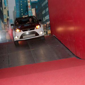 Modified Ford Fiesta RS WRC on a city street, racing through narrow alleys. Bright neon lights and urban backdrop