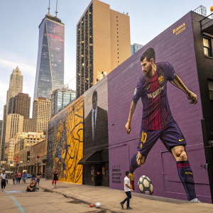 A large mural in downtown Chicago featuring Lionel Messi. Street art style with vibrant purple and gold hues. Urban background with graffiti