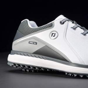 A close-up shot of the FJ Pro SL golf shoe. White upper with grey accents. Grey panel on side. Textured outsole with FJ logo. The shoe stands out against a minimalist black background.