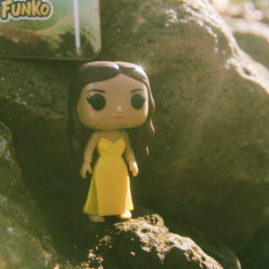 Olivia Rodrigo Funko Pop! vinyl figurine. Bright, neon pink backdrop. Character wearing a vibrant yellow dress. Funko logo visible