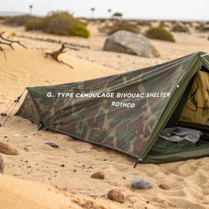 Rothco's G.I Type Camouflage Bivouac Shelter sprawled on golden sand. Partially visible pattern. Brand logo printed on fabric