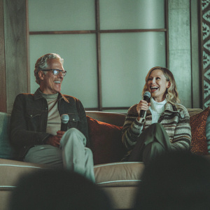 Kristen Bell and Ted Danson, smiling and engaged in conversation. Sitting on a couch during a talk show