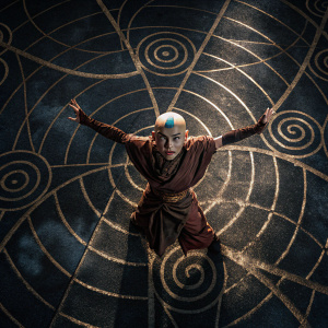 3D render of Aang from Avatar: The Last Airbender in an action pose. Dark backdrop with intricate golden swirl patterns