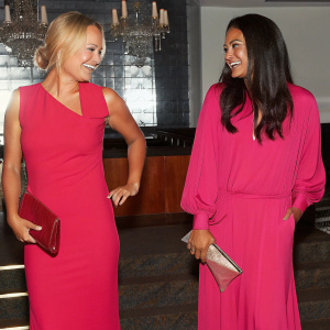 Malin Akerman and Emmanuelle Chriqui at a glitzy gala. Both actresses are beaming, dressed in glamorous evening wear. Lavish ballroom with chandeliers.