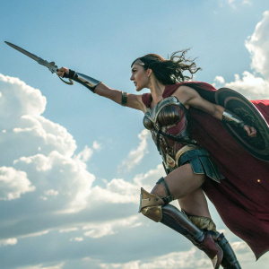 Gal Gadot as Wonder Woman in action pose. Flying scene with bright skies and fluffy clouds in the background.