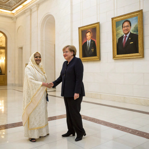 Formal portrait of Angela Merkel and Pratibha Patil shaking hands. Luxurious white marble hallway. Golden framed portraits hanging on the walls.