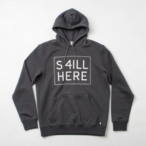 Charcoal gray hoodie featuring 's-4ill here' in bold square block font. Streetwear style with drawstring hood and front design.