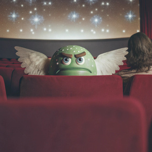 A digital artwork promoting NEXON's MapleStory Guardian Angel Slime Movie. The central character is a green, angry slime creature with angel wings. Set against a vibrant purple backdrop with twinkling stars. The whimsical and cartoonish style emphasizes the fantasy theme.