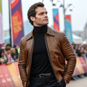 Henry Cavill, in a stylish brown leather jacket and black turtleneck, promoting his latest film at an outdoor festival. Crowds and banners in the background.