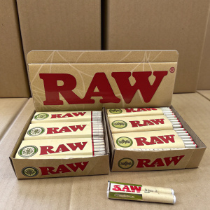 Multiple boxes of RAW rolling papers arranged neatly on a plain brown cardboard backdrop. Bold red text reads 'RAW'.