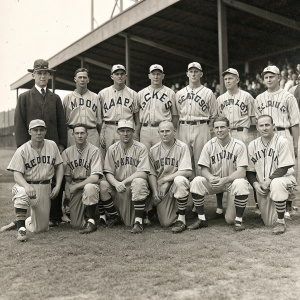 1934 Kansas City Monarchs team photo. Baseball players in vintage uniforms, standing and kneeling in a traditional pose. Team name 'Monarchs' visible on jerseys.