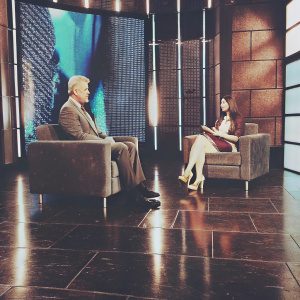 Bill Clinton and Tabitha Sorenson appearing on a talk show. Modern studio set with large screens displaying dynamic visuals and bold graphics.