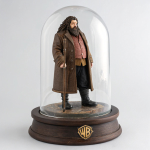 Collectible action figure of Rubeus Hagrid. Dark hair, beard, and mustache. Clad in brown overcoat, black boots, and carrying a staff. Encased in transparent, protective display case with a detailed, dark wooden base featuring the Hogwarts emblem.