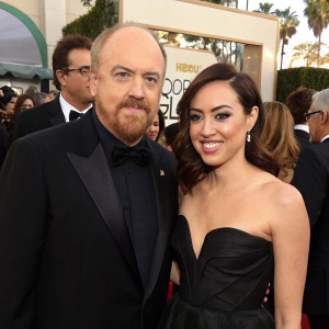 Louis C.K. and Aubrey Plaza at the Golden Globe Awards. Louis C.K. in black tuxedo, Aubrey Plaza in a stylish black gown, holding glasses, surrounded by celebrities