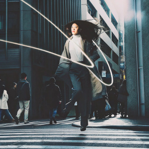 In the bustling streets of Tokyo, a female protagonist from *Berserk* anime series, with flowing dark hair and intense expression, is captured mid-action. Dynamic lines and vibrant colors evoke a sense of movement and power.