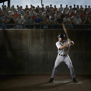 Michael Brantley, wearing the Houston Astros jersey number 23, in a batting stance. The stands filled with enthusiastic fans, the backdrop a vibrant green fence with sponsor logos. Sports action shot