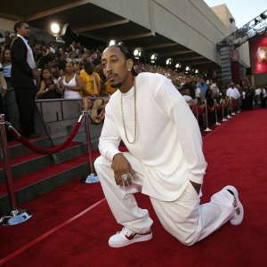 Ludacris at the 2004 MTV Movie Awards, dressed in a white long-sleeved shirt and sneakers, posing in front of a bustling crowd at a concert.