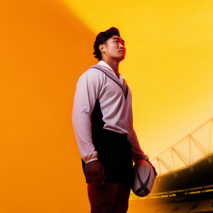 Loki Crichton, Asian male rugby player for Worcester Warriors. Standing confidently in a blurred stadium setting.