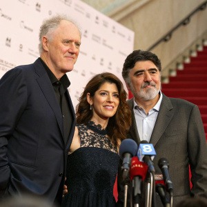 John Lithgow, Marisa Tomei, and Alfred Molina stand together at a press conference. Red carpet backdrop