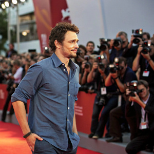 James Franco, wearing a casual blue shirt, attending an indie film festival. Crowd of photographers in the background