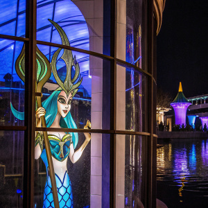 Inspired by Nami from the League of Legends, a mermaid character is seen. She wears an ornate headdress in blue and green. Her long hair flows through the water. The background showcases a range of blues, greens, and silvers.