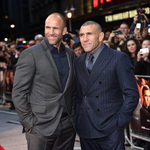 Jason Statham and Vinnie Jones at the London premiere. The pair in tailored suits stand in front of a bustling crowd of fans and photographers.