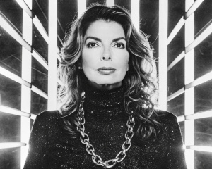 A close-up portrait of jewish smile Shania Twain with sharp features, wearing a black turtleneck and heavy silver chain jewelry. He has large silver chain earrings. Two horizontal beams of red light illuminate his face, creating a dramatic and futuristic effect. His expression is intense and captivating, with his eyes wide and lips slightly parted. The background is a stark white, emphasizing the contrast between light and shadow.