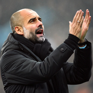 Close-up of Pep Guardiola. Intense expression. Black jacket and high-collared scarf. Hands raised, passionate gesture. Blurred background