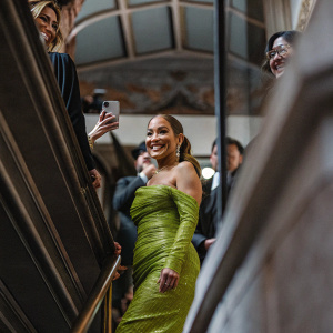 Jennifer Lopez, celebrity, at award show. Wearing shimmering emerald green dress. Smiling, posing among crowd.